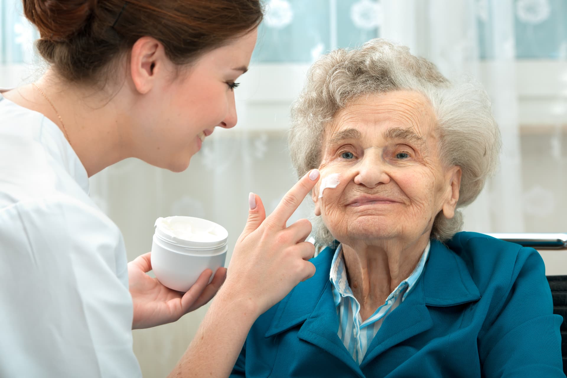 Caregiver helping a senior woman with her daily skin care routine